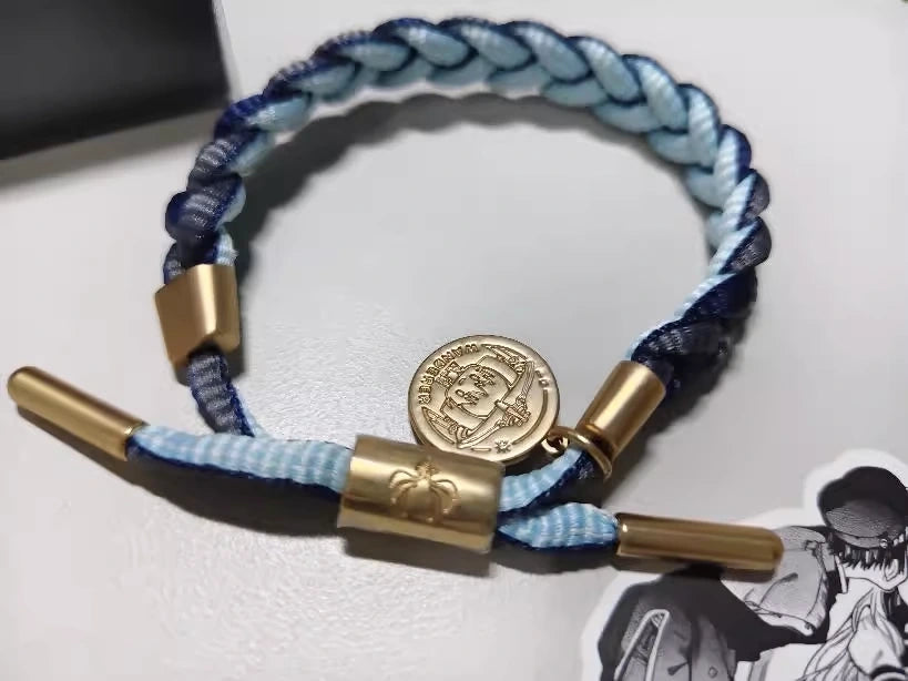 Customer photo of a dark blue Genshin Impact character-inspired braided bracelet with braided cord and engraved metal charm on desk