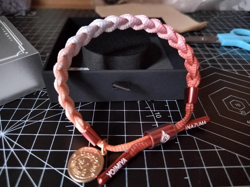 Customer review photo of a pink and red Genshin Impact character-inspired braided bracelet with Inazuma themed metal details