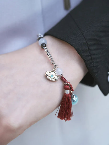 Genshin Impact Shenhe bracelet close up featuring icy blue beads braided cord and tassel accents