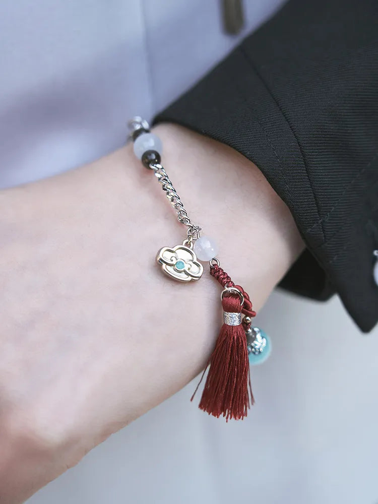 Genshin Impact Shenhe bracelet close up featuring icy blue beads braided cord and tassel accents